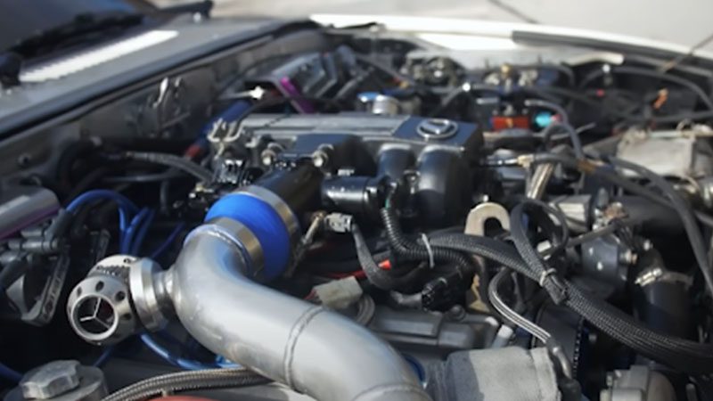 Close-up of a Mazda RX-7 engine bay, showcasing the rotary engine and performance modifications.