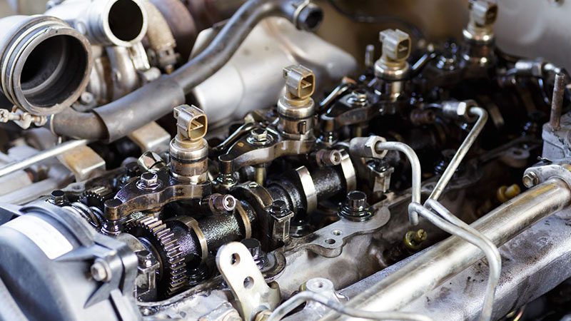 Repair of an old engine’s fuel injection system, showing components of a common rail diesel injection system on a workbench.