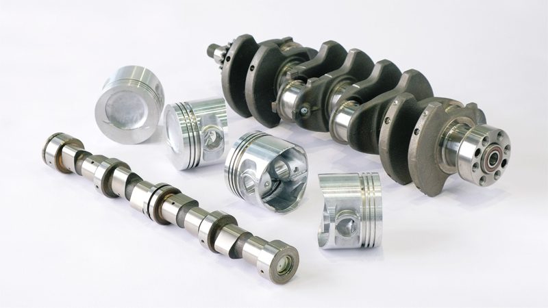 Close-up of a crankshaft, camshaft, and pistons, showcasing key internal engine components in detail.