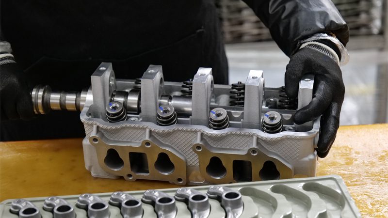 Close-up of a cylinder head assembly showing valve springs, rocker arms, and intake/exhaust ports.