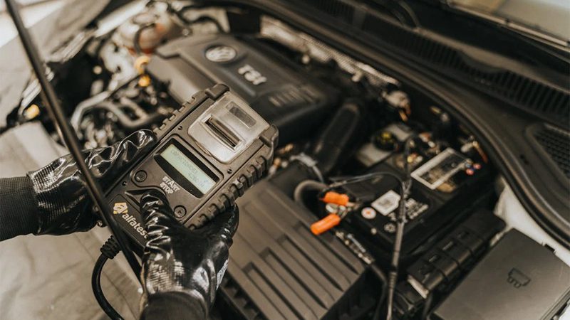 Mechanic diagnosing a car engine with a diagnostic tool, showcasing technical expertise and automotive care.