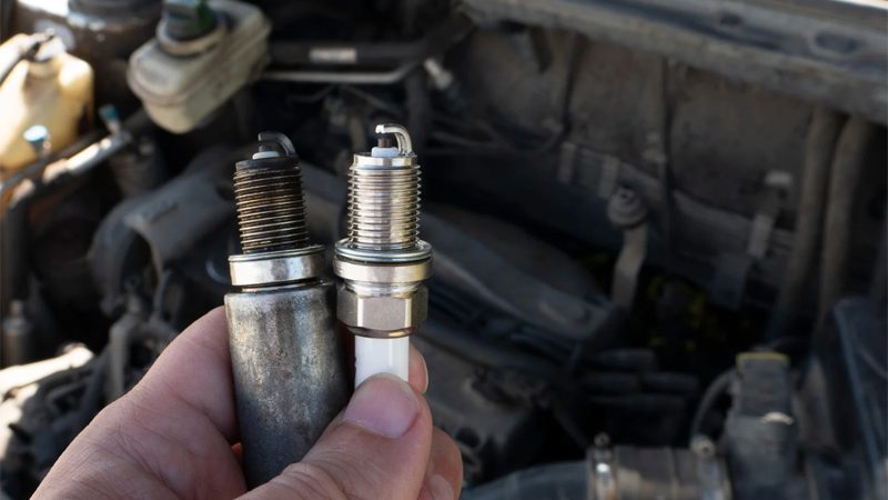 Replacing new spark plugs on a car engine during an engine tune-up in the workshop.