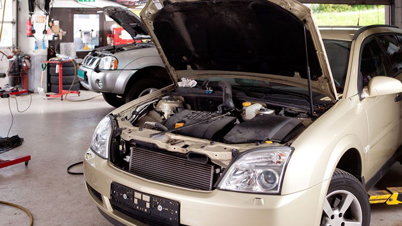 Car in repair shop with hood up, illustrating the need for professional service to fix limp mode issues.