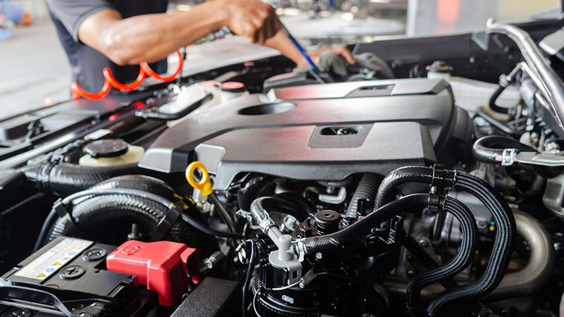 Mechanic working on a clean car engine after engine bay washing and maintenance.