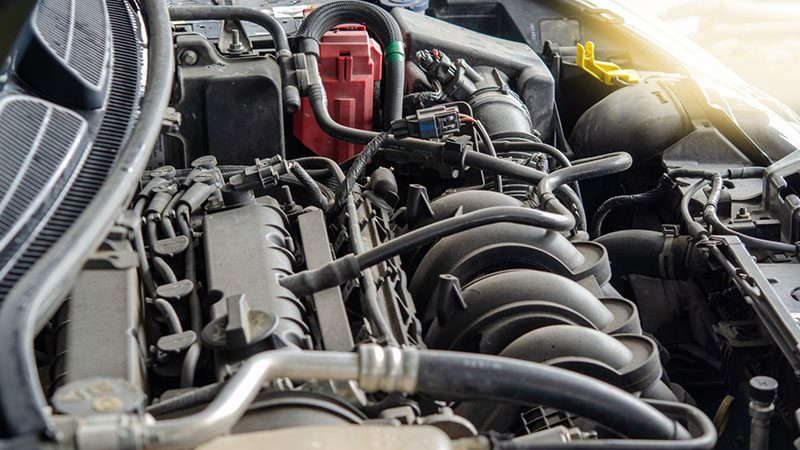 Close-up of a dirty car engine showing buildup of grime and debris on components.