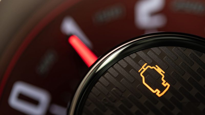 Close-up of illuminated check engine light on car dashboard, warning of possible engine malfunction