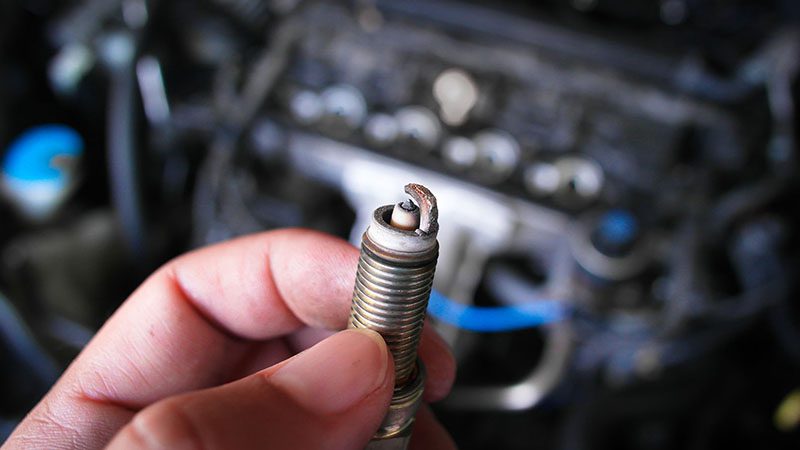 Close-up of a faulty spark plug showing signs of engine misfire.