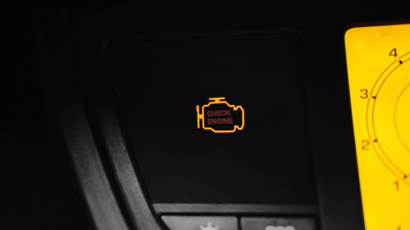 Close-up of check engine light icon illuminated on car dashboard.