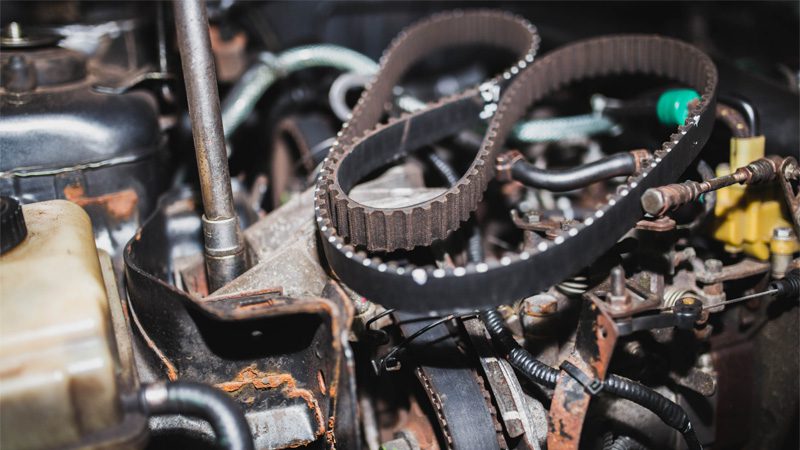 Mechanic replacing the timing belt in a car engine.