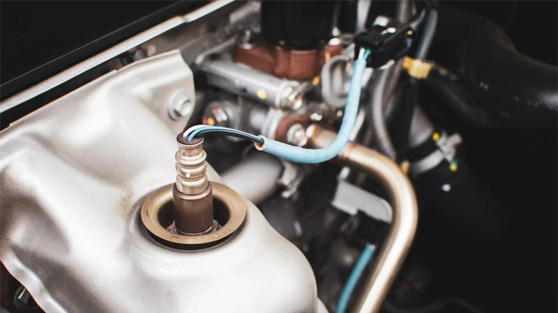 Close-up of an oxygen (O2) sensor installed in a car’s exhaust pipe.