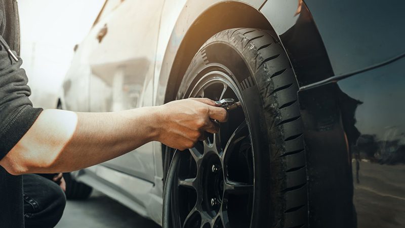 Checking tire pressure on a car, ensuring optimal tire inflation for better fuel efficiency and vehicle performance.
