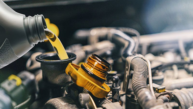 Pouring fresh motor oil into a car engine during a routine oil change.