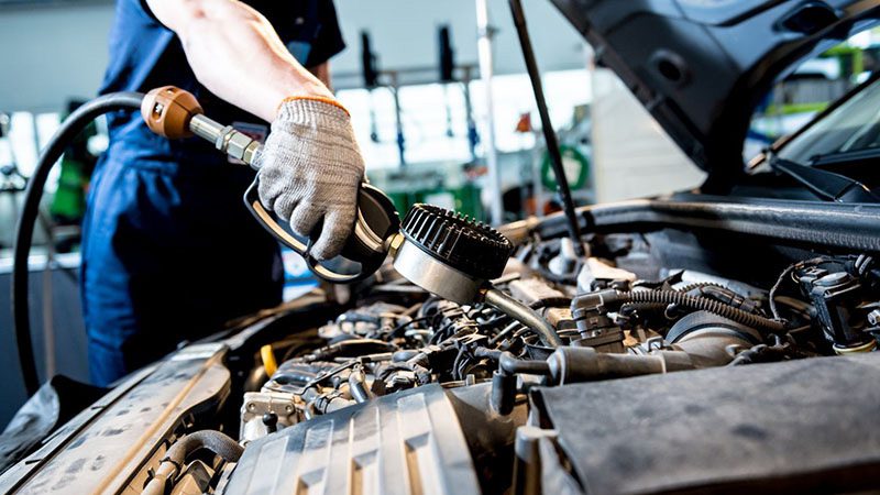 Mechanic inspecting the motor oil of a car to ensure proper lubrication and engine performance.