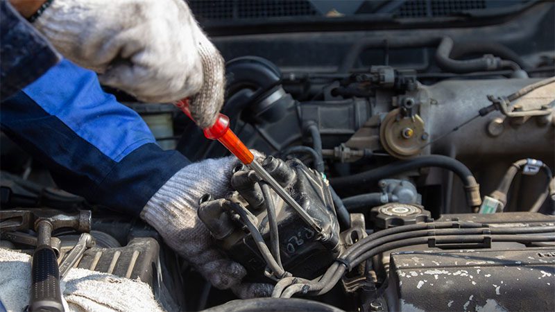 Mechanic repairing an engine, focusing on fixing the coil pack.