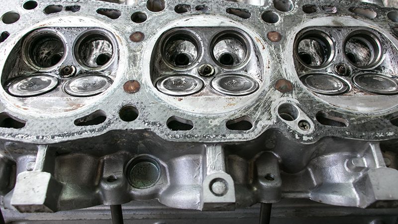 Close-up of a cylinder head highlighting valve seats and combustion chambers.