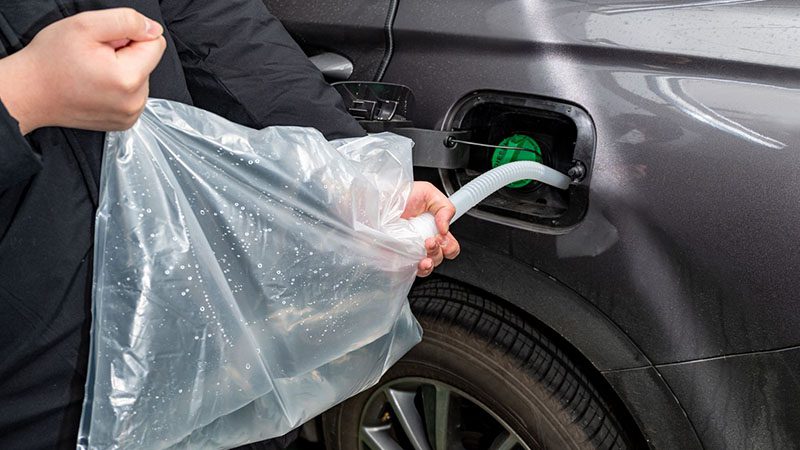 Man refilling Diesel Exhaust Fluid (DEF) into vehicle tank.