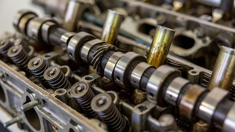 Close-up of a camshaft in an engine assembly, showing valve timing components and cam lobe detail.
