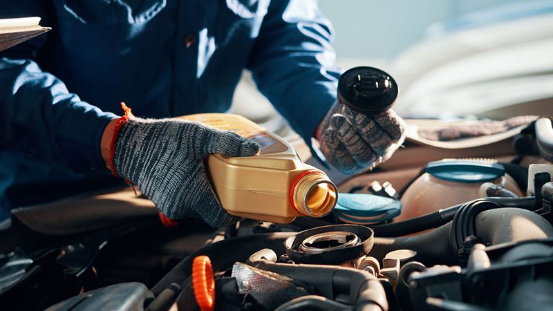 Mechanic performing an oil change on a vehicle, draining old engine oil as part of routine maintenance