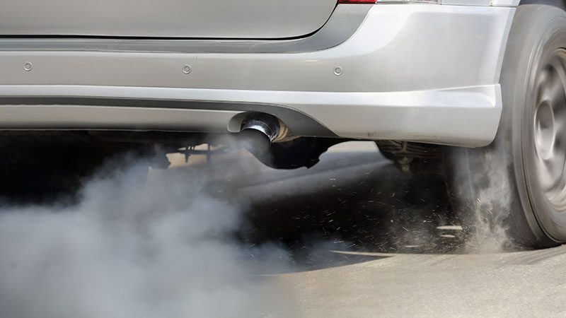 Smoke coming out of a car’s exhaust, suggesting a potential engine issue such as fuel, oil, or coolant burning