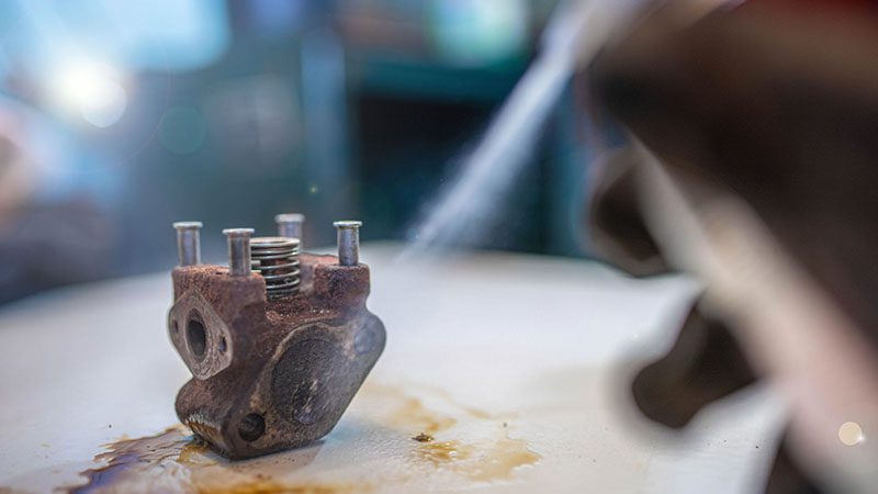 Cleaning an EGR (Exhaust Gas Recirculation) valve with cleaner spray to remove carbon deposits and improve engine performance.