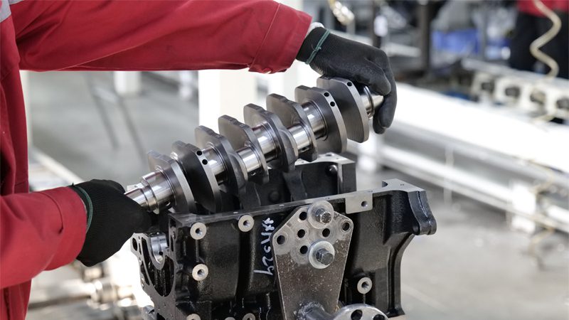 Mechanic installing a crankshaft into the engine cylinder block on Nanjing Woda's factory engine assembly line.