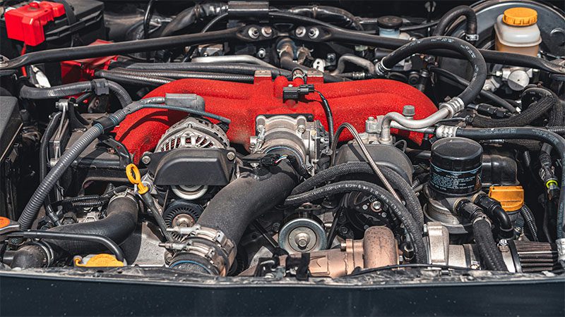 Close-up of a car engine displaying key components like the intake manifold, belts, and hoses.