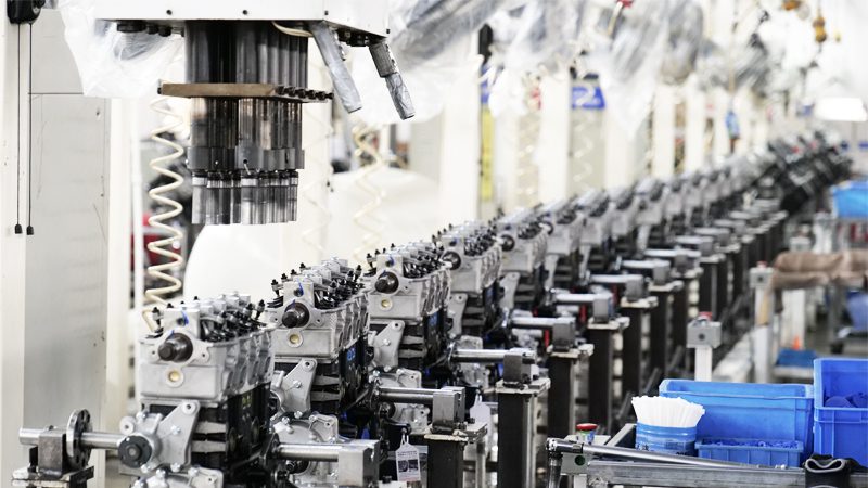 Auto engine assembly line at Nanjing Woda Auto Technology Co., Ltd. factory with technicians working on engine components.