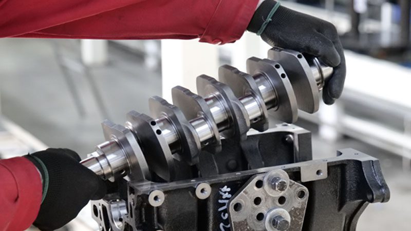 Mechanic installing a crankshaft into the engine to ensure proper functionality and performance.