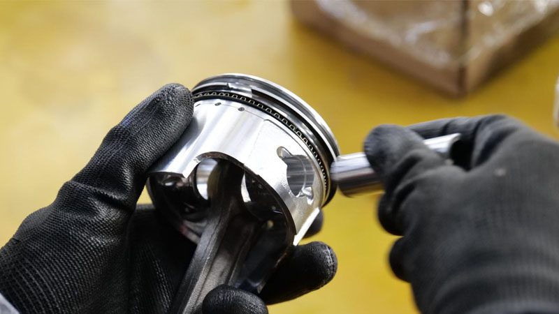Mechanic carefully inspecting new piston rings before installation during the engine overhaul process.