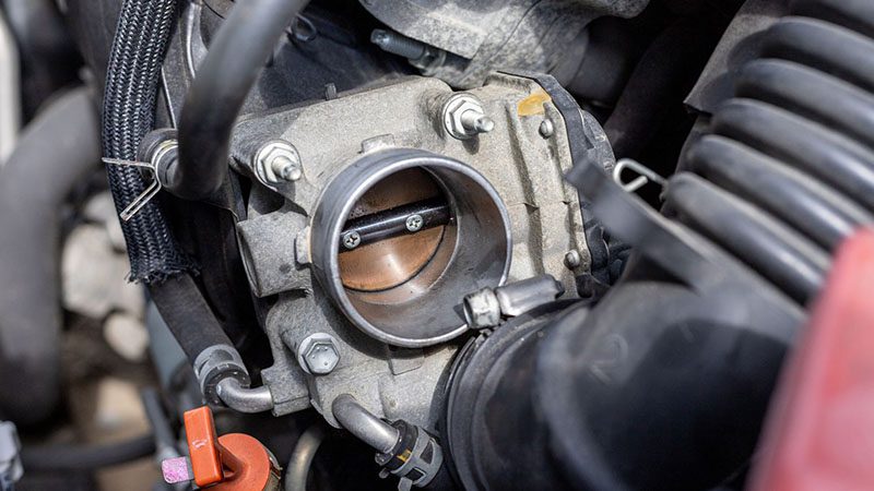 Close-up of a car throttle body being cleaned, showing carbon buildup removal to fix engine power reduced issues.