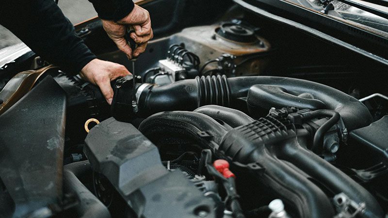 Auto mechanic inspecting a car engine, checking for issues related to reduced engine power or sensor faults.