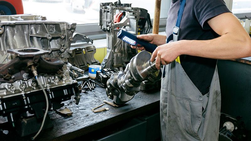 Mechanic rebuilding an engine in a workshop with tools and components laid out