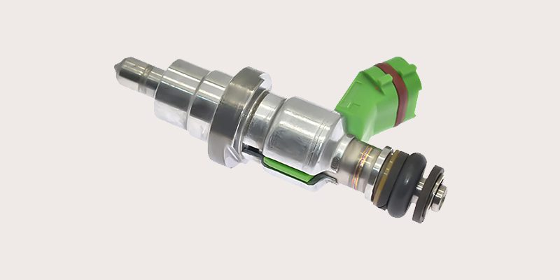 Close-up of a car fuel injector, showing the nozzle and electrical connector.
