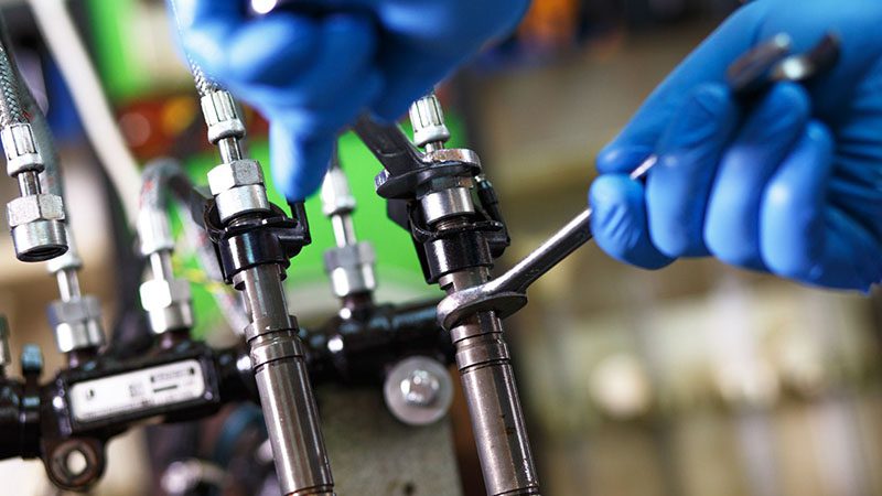 Mechanic testing a diesel injector for performance and contamination issues during engine diagnostics.