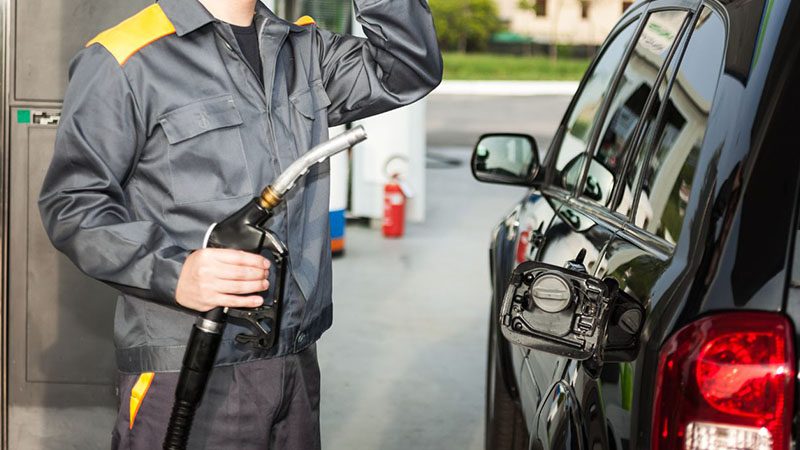 Gas station attendant refueling a vehicle.
