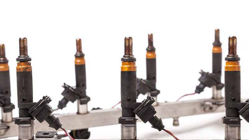 Close-up of a car fuel rail with injectors for an eight-cylinder gasoline engine, isolated on a white background