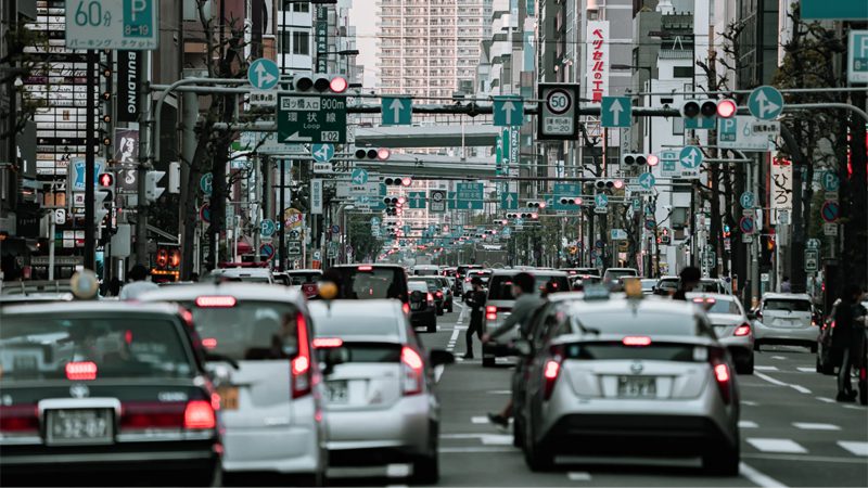 Car driving through a busy urban environment with city buildings in the background.