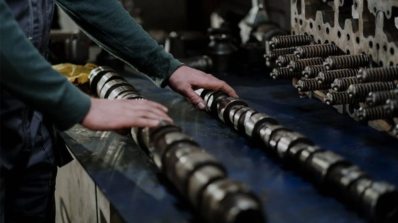 A mechanic carefully handling a camshaft, demonstrating the precision and expertise required in engine maintenance and repair.
