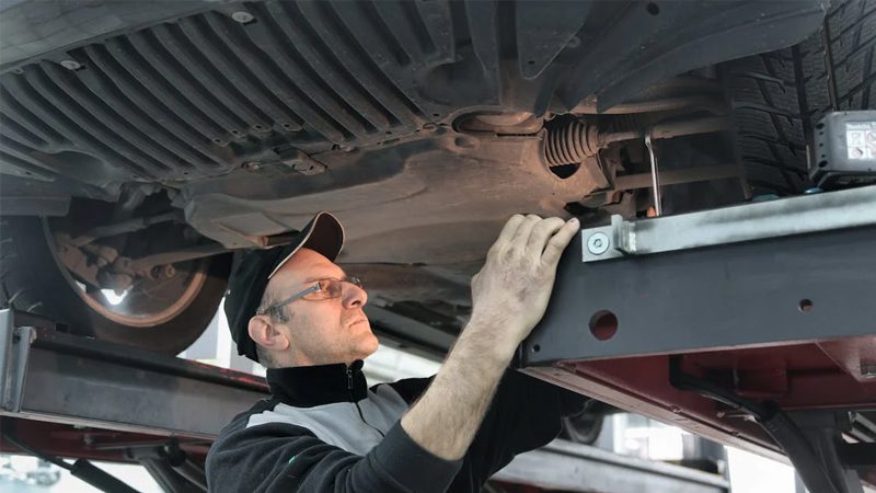 A mechanic inspecting and working on a car, highlighting the detailed care and skill involved in automotive repair and maintenance.
