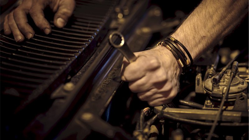 A mechanic using a wrench to work on a car, demonstrating the skill and precision involved in vehicle repair and maintenance.