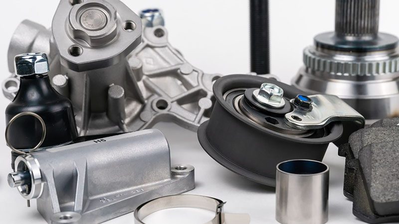 Assorted auto spare parts including suspension and engine components displayed on a white background, representing an auto parts store inventory.