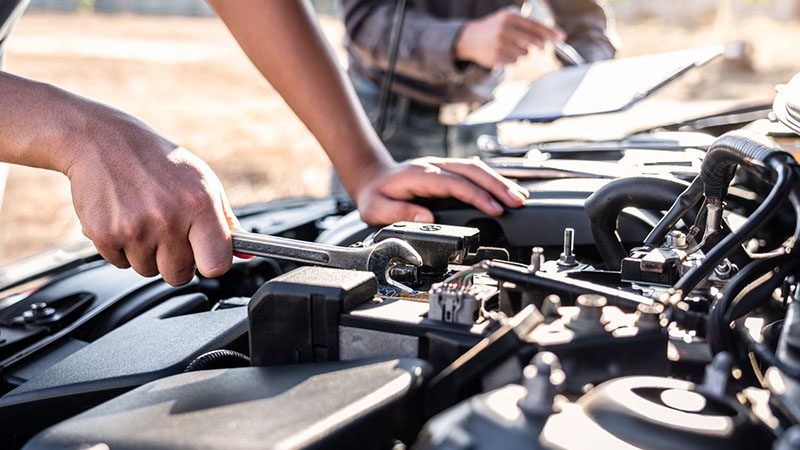 Technician team performing car maintenance and repair service, mechanic using wrench during vehicle inspection.