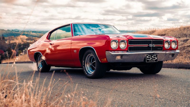 Red Chevrolet Camaro on brown field during daytime.