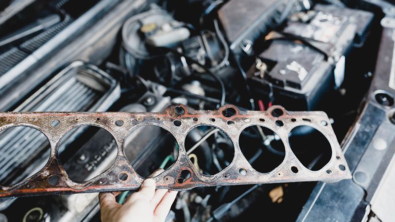 Close-up view of a faulty head gasket, showing signs of wear and potential failure in an engine.