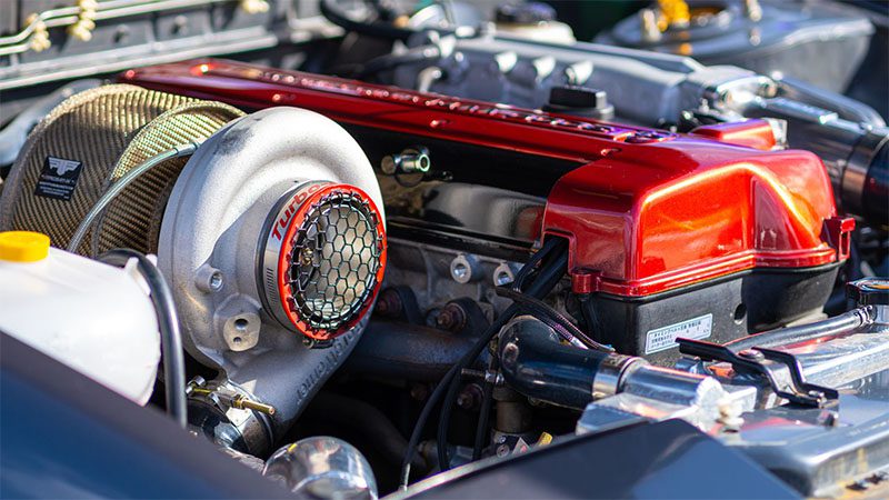 Close-up view of a car engine equipped with a turbocharger, showcasing detailed components and metallic finish.
