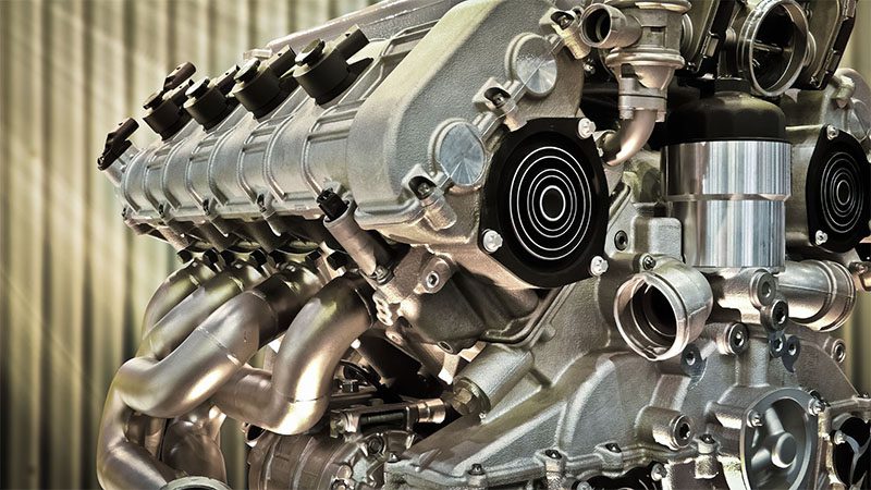 Partial view of an automobile engine against an industrial metal sheet background, highlighting mechanical detail and durability.