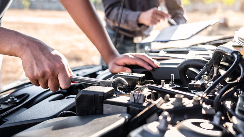 Technician team performing auto repair and maintenance service, using tools to inspect and fix a vehicle