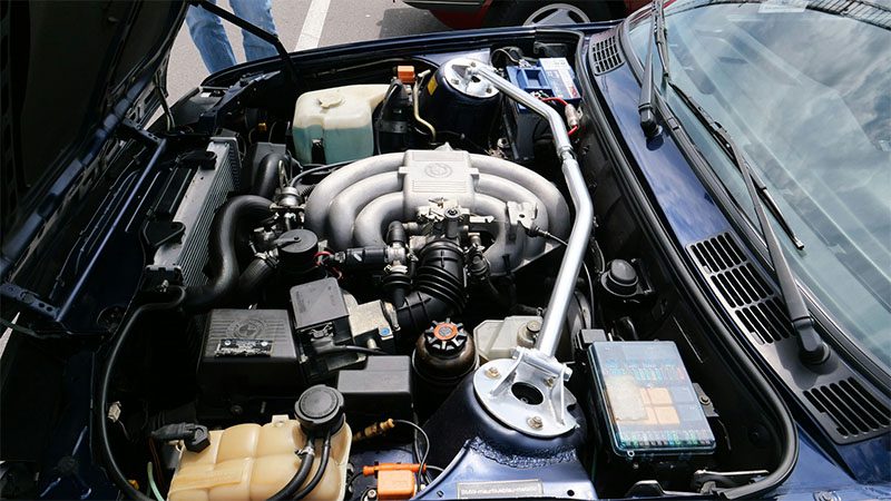 Close-up view of a car with the hood lifted, revealing the engine inside