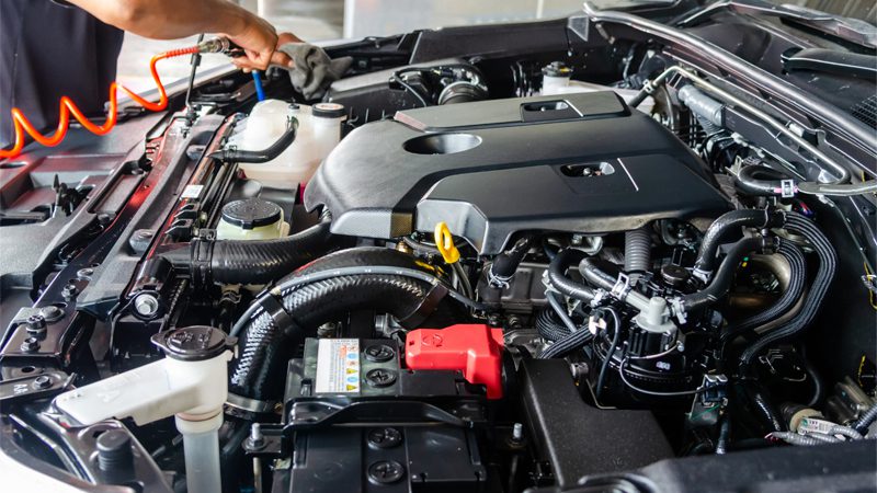 Mechanic working on a car engine during maintenance or repair service