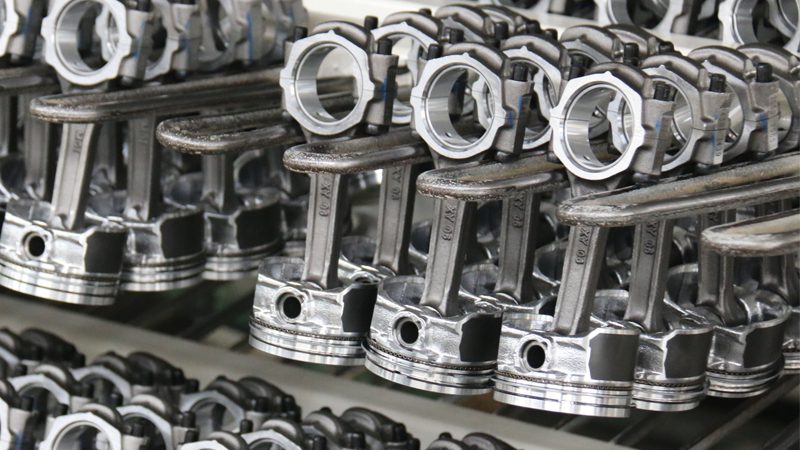 Close-up of car engine pistons, showing piston heads, connecting rods, and rings.